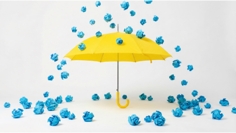 balled up papers falling from the top of picture onto an umbrella