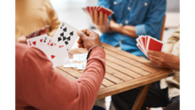 peoples hands holding playing cards